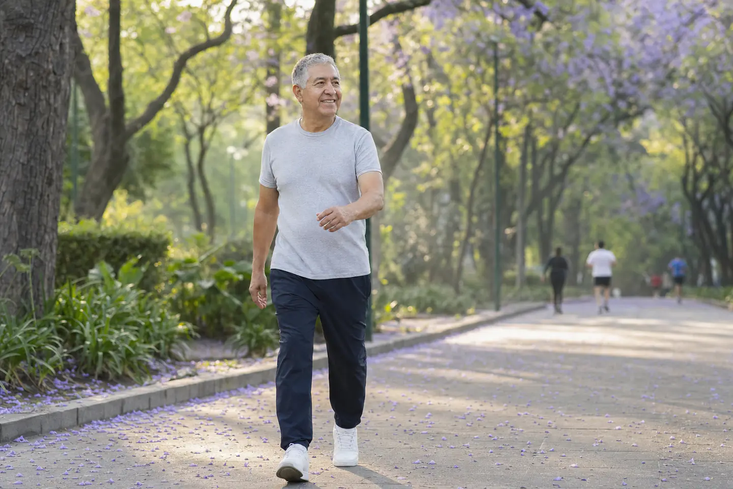 Hombre de 60 años camina a paso firme por un parque en la mañana